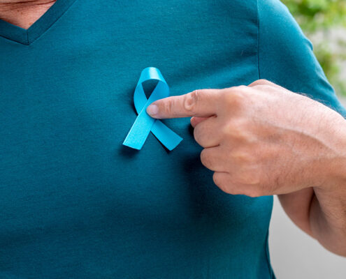 Hombre de mediana edad sosteniendo el lazo azul del cáncer de próstata en el corazón